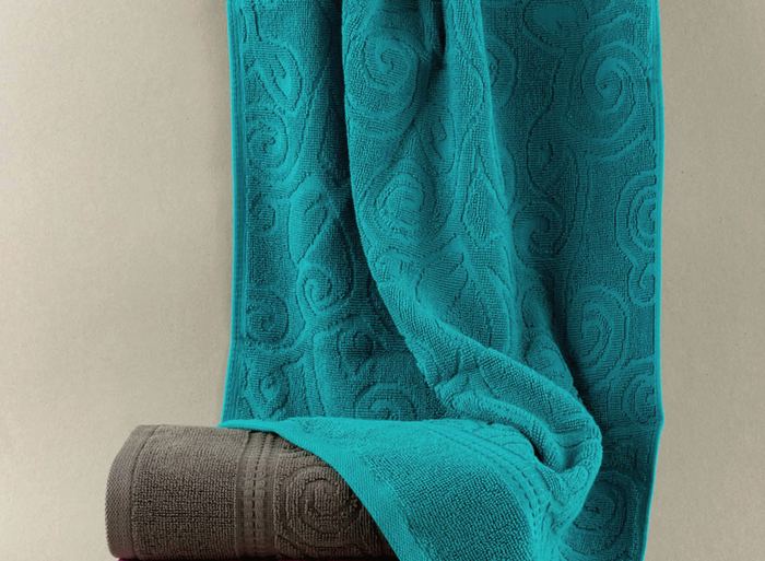 Teal towel draped over folded grey and magenta towels