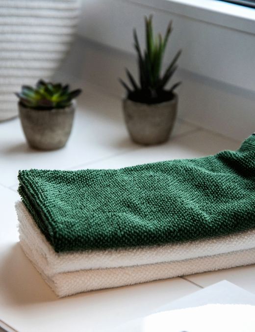 Green and white folded hand towels near succulents