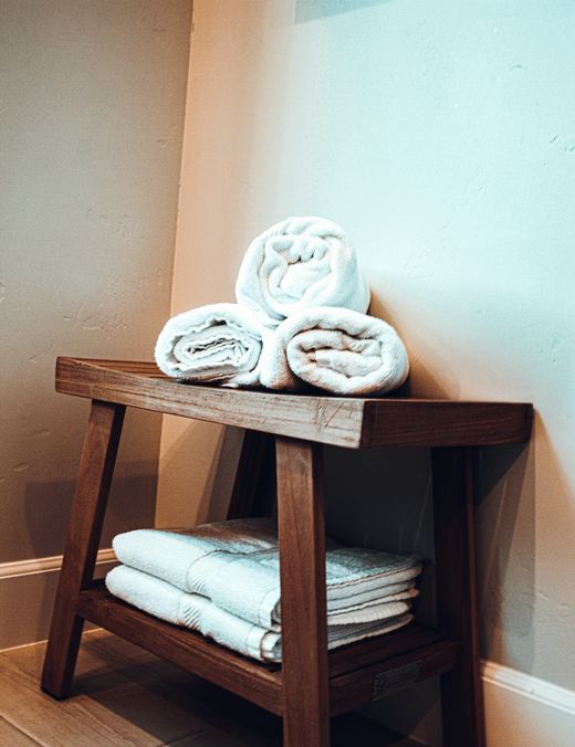 Rolled white hotel towels on a wooden bench